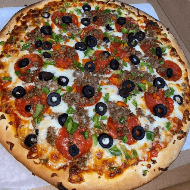 Pizza topped with pepperoni, black olives, green peppers, and sausage on a cardboard box.