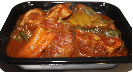 Tray of spicy curry with meat, bell peppers, and rich red sauce.