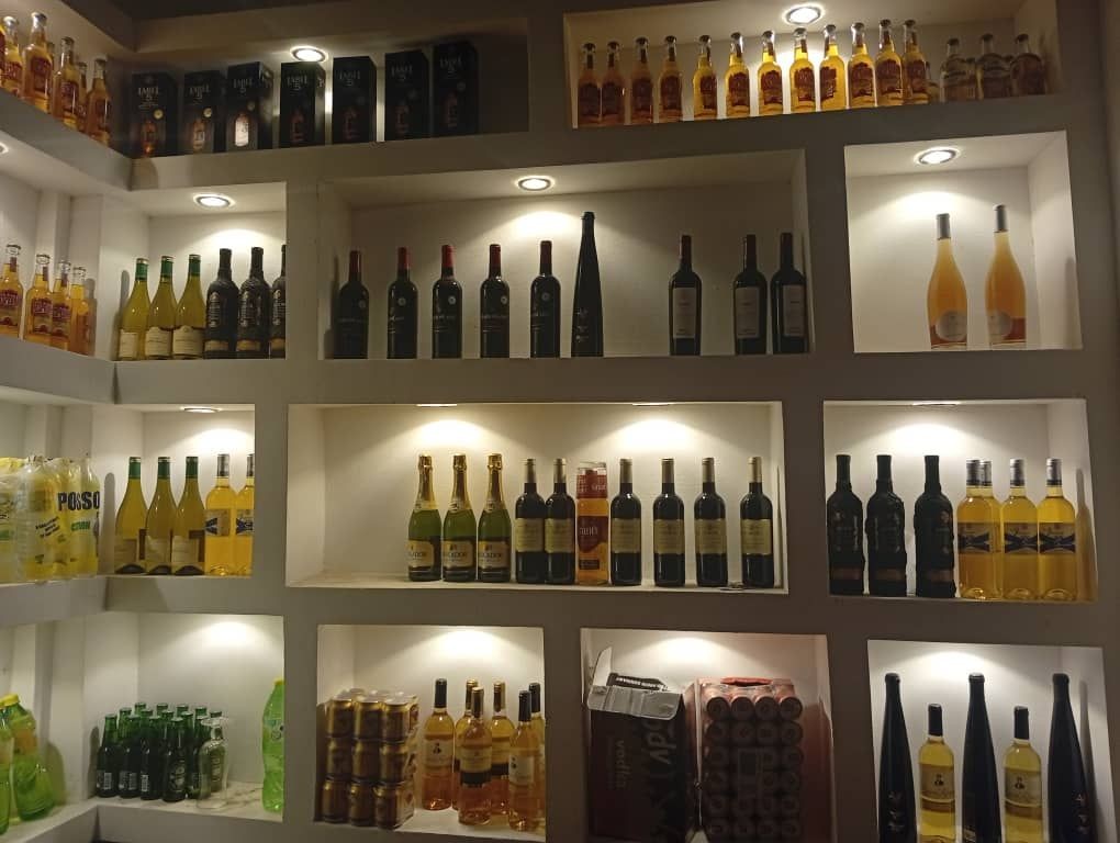 Shelves filled with various bottles of wine and alcohol, illuminated by spotlights.