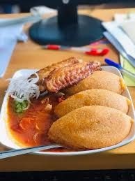 Plate of empanadas with grilled chicken and sliced onions on a wooden table.