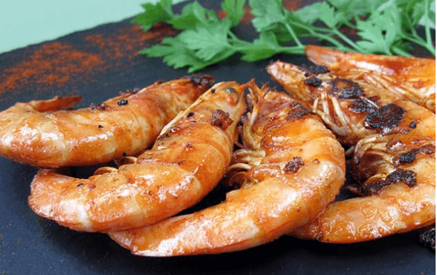 Grilled shrimp on a slate plate garnished with fresh herbs.