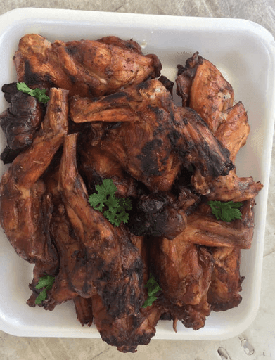 Plate of grilled meat garnished with sprigs of fresh parsley.