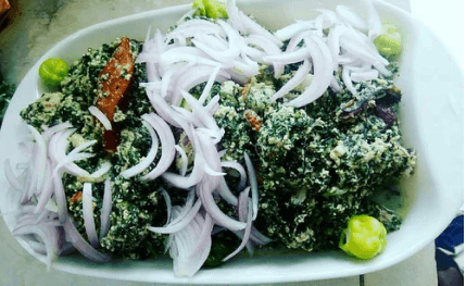 Plate of Ewedu soup garnished with sliced onions and green peppers.